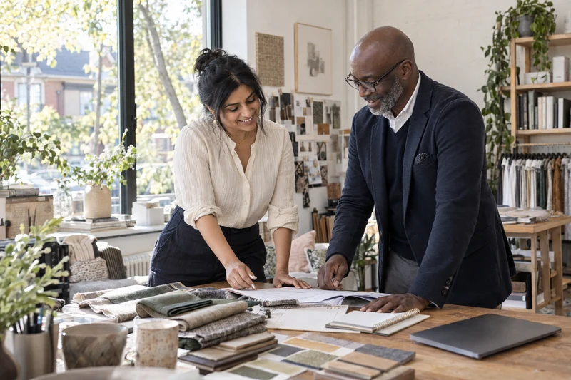 Smiling business owner and advisor reviewing paperwork in a design studio